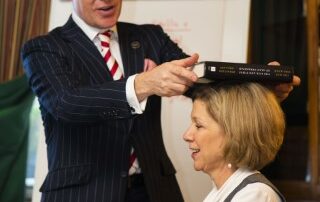 Philip demonstrates correct sitting posture with one of his students by placing a book on her head